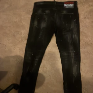 Svarta jeans med slitna detaljer - Snygga svarta jeans med slitna detaljer och en modern look. De har en knappgylf och klassisk femficksdesign. Perfekta för en trendig stil.