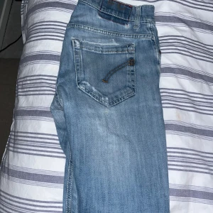 Dondup George  - Snygga blå jeans med coola slitningar och en klassisk femficksdesign. Perfekta för en avslappnad stil. Midjan är normal och byxorna har en knappgylf.