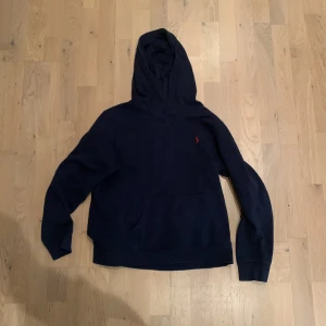 Mörkblå hoodie från Polo Ralph Lauren - Säljer en snygg mörkblå hoodie från Polo Ralph Lauren. Den har en klassisk design med en liten röd logga på bröstet och en praktisk magficka. Perfekt för en avslappnad stil. Pris kan diskuteras!