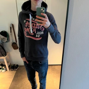 Superdry hoodie 🍾 - Tjenare, Säljer en snygg mörkblå hoodie från Superdry, skicket är väldigt bra skulle säga 8/10. Storlek S han på bilden är 180 cm och då sitter den lite litet. Släng iväg dem för frågor! 🙌🍾