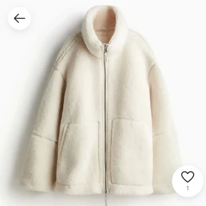 Vit teddyjacka med dragkedja - Mysig vit teddyjacka med dragkedja och hög krage. Perfekt för kyliga dagar med sin fluffiga och varma design. Jackan har två stora fickor framtill och en avslappnad passform.