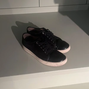 Svarta sneakers från Lanvin - Snygga svarta sneakers från Lanvin med vit sula och klassisk snörning. Perfekta för en stilren look.  Pris kan diskuteras😊.Låda och påse ingår.