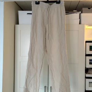 Beige byxor från Gina Tricot - Säljer ett par bekväma beige byxor från Gina Tricot. Byxorna har en loose passform med elastisk midja och knytband för justering. Perfekta för en avslappnad stil eller som pyjamas byxor