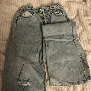 Ljusa höjmidjadejeans med slitningar från H&M. 💙 - Säljer ett par ljusa jeans med hög midja och breda ben med en öppning.  Finns band där man kan dra åt i midjan. 🦕🦋