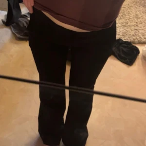 Lågmidjade Svarta kostymbyxor - Snygga svarta kostymbyxor med en klassisk design. Byxorna har en flare lowwaist passform och är perfekta för en stilren look. De har en dragkedja och knapp framtill för enkel stängning. Jätte fina enda skavanken är på baksidan där de e ihop sytt💕nypris ca 500kr