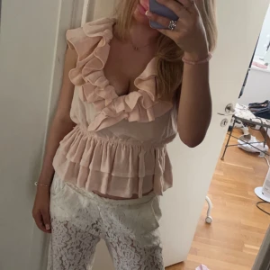 Rosa volangtopp - Söt rosa topp med volanger. Små sminkfläckar på kragen som inte syns vid användning. Storleken är officiellt 40, men jag är själv i xs-m storlek och det passar mig
