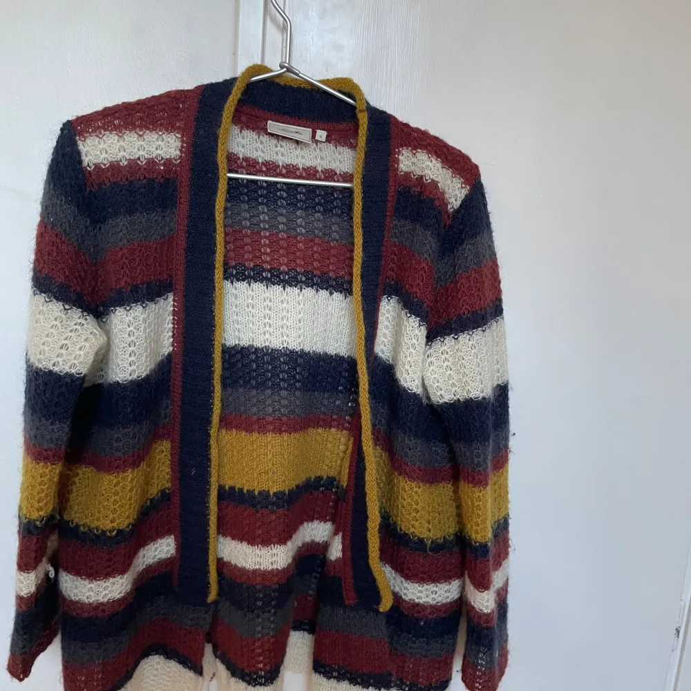Säljer en mysig flerfärgad stickad kofta från Boomerang. Koftan har ett randigt mönster i rött, blått, vitt och gult. Den är tillverkad i en blandning av nylon, kidmohair och ull, vilket gör den både varm och bekväm. Perfekt för kyliga dagar! Passar mig som är xs men passar också s och xxs Den är perfekt i armarna för mig som är 160 cm💕💕💕🫶🏻. Neuletakit & Villapaidat.