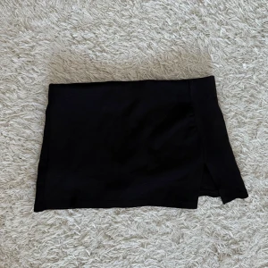 Svart kjol från Bershka - Snygg svart kortkjol från Bershka med en liten slits på sidan. 