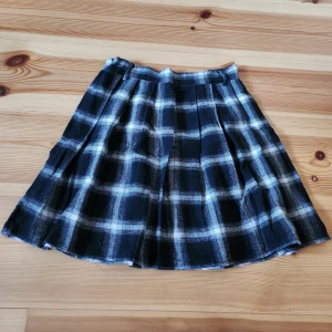 Svart och vit rutig volangkjol - Snygg svart och vit rutig kjol med veckad design. Perfekt för en stilren look. Kjolen har en klassisk passform och är lätt att matcha med olika toppar.