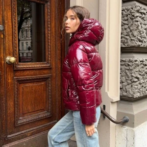 Vinröd pufferjacka med huva - Nelly Everyday shiny puffer jacket röd vinröd jacka. Jackan har en dragkedja framtill och är perfekt för kyligare dagar. Storlek M.