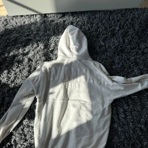 Vit hoodie från Calvin Klein Jeans - Säljer en stilren vit hoodie från Calvin Klein Jeans. Den har en klassisk design med en stor ficka framtill och justerbar huva. Perfekt för en avslappnad look.