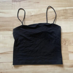 Svart linnetopp från Gina Tricot - Säljer en stilren svart linnetopp från Gina Tricot. Toppen har smala axelband och en enkel design som passar perfekt till olika outfits. Perfekt för varma dagar eller som ett lager under andra plagg.