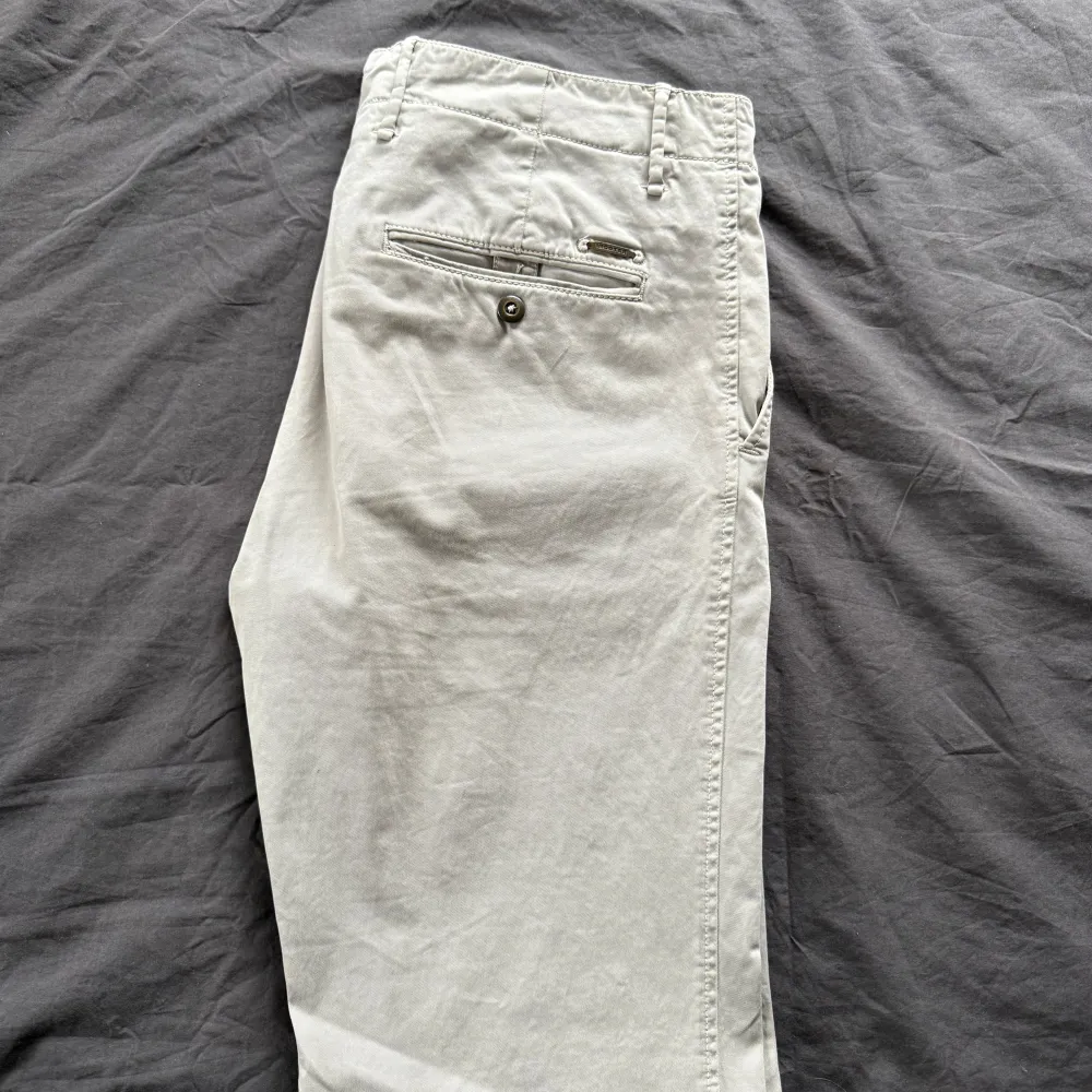Snygga beige chinos från Incotex i en slim fit-modell. Byxorna har en klassisk design med knappar och en diskret ficka bak. Perfekta för en stilren look. Nypris 3399.. Farkut & Housut.