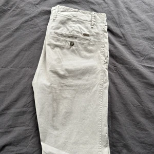 Beige chinos från Incotex - Snygga beige chinos från Incotex i en slim fit-modell. Byxorna har en klassisk design med knappar och en diskret ficka bak. Perfekta för en stilren look. Nypris 3399.