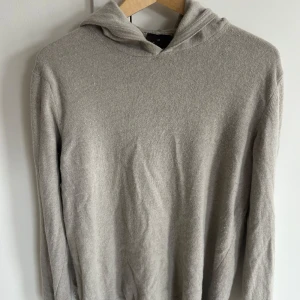 Beige hoodie från Oscar Jacobson - Säljer en stilren beige hoodie från Oscar Jacobson. Tröjan är tillverkad i ett mjukt material och har långa ärmar. Perfekt för en avslappnad och bekväm stil.