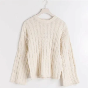 Vit stickad tröja - Säljer en mysig vit stickad tröja med kabelstickat mönster. Tröjan har långa ärmar och en rund halsringning. Perfekt för kyliga dagar! Den är använd, så den är lite nopprig. En blandning mellan vit och cremefärgad 