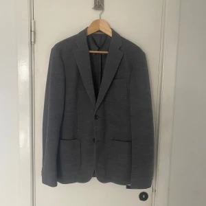 Grå stickad kavaj från Uniqlo - Säljer en stilren grå kavaj från Uniqlo i storlek M. Kavajen har en klassisk design med två knappar framtill och är tillverkad i ett mjukt material som ger en bekväm passform. Perfekt för både formella och avslappnade tillfällen. Passar storlek M perfekt. Skriv om ni har några övriga frågor🙌