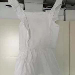 Vit ärmlös topp från cubus - Säljer en söt vit ärmlös topp från Woom (cubus) Toppen har en smockad överdel och volangdetaljer vid axlarna. Perfekt för varma sommardagar! 🌞 storleken är som xs/s