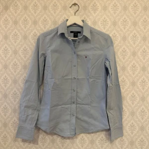 Ljusblå skjorta från GANT - Snygg & klassisk figursydd skjorta från GANT i storlek 34 (lite stretchig i tyget) Knappt använd så i mycket bra skick. Har inte kunnat använda denna efter graviditet och såg nu ett litet märke i tyget bak. Inget som stör idag men vore nog bra att stärka på insidan. Nypris 1400kr.