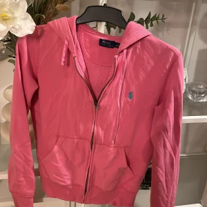 Rosa hoodie från Polo Ralph Lauren - Säljer en snygg rosa hoodie från Polo Ralph Lauren med dragkedja och huva. Den har en liten blå logga på bröstet. Några fläckar vid slutet på en av armarna men går att tvätta😊. Hör av dig vid intresse! 💖