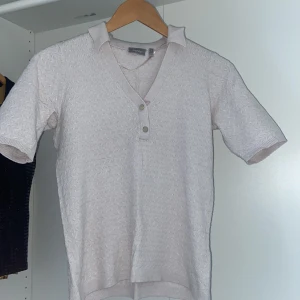 Vit kortärmad tröja från Fransa - Säljer en stilren vit kortärmad tröja från Fransa. Tröjan har en v-ringad design med knappar framtill och ett diskret mönster. Perfekt för en avslappnad look.