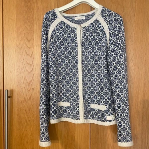 Blåvit stickad kofta Odd Molly - Säljer en blåvit stickad kofta från Odd Molly med snyggt geometriskt mönster. Koftan har långa ärmar, rund hals och ribbade kanter. Perfekt att slänga på sig för en chill och stilren look.