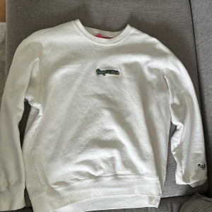 Vit sweatshirt från Supreme - Säljer en vit sweatshirt från Supreme med broderad logga på bröstet och siffran *94 på ärmen. Tröjan har rund hals och långa ärmar. Klassisk och stilren modell med liten röd Supreme-tag vid nederkanten.