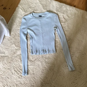 Ljusblå ribbad tröja Gina Tricot - Supersnygg ljusblå ribbad tröja från Gina Tricot. Modellen är tight och croppad med långa ärmar och rund halsringning. Perfekt att styla med jeans eller kjol för en fräsch look. Materialet är mjukt och stretchigt, vilket gör den riktigt bekväm. Jätteskön på och sitter bra! 💕👌🏼