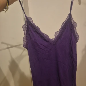 Lila ribbad linnetopp med spets - Supersöt lila linnetopp med smala axelband och v-ringning. Toppen är ribbad och har fina spetsdetaljer längs urringningen och runt axlarna. Perfekt att styla med jeans eller kjol för en trendig look.💐💐💐. 🌸passar hela året runt och fångar definitivt allas uppmärksamhet🌸. priset kan diskuteras cupcakes🫶♡