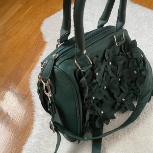 Jätte fin mörkgrön handväska med fina 3D blommor på framsidan 💗 - Ny, använd ett fåtal gånger. Jätte fina detaljer och fin färg. 