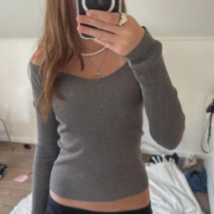 Grå ribbad offshoulder tröja H&M  - Superfin grå ribbad tröja från H&M i offshoulder-modell. Sitter tight och har lång ärm, perfekt för dig som gillar en stilren och enkel look. Materialet är mjukt och stretchigt, vilket gör den riktigt skön att bära. 🩵