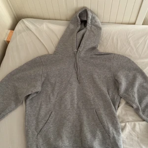 Grå hoodie Mira Paris med tryck! Pris kan diskuteras! - Grå hoodie från Mira Paris med svart tryck på ryggen där det står 'Mi Amor' och ett hjärta genomborrat av en pil. Tröjan har huva med snörning och en stor magficka. Tillverkad i ekologisk bomull, perfekt för chill dagar.