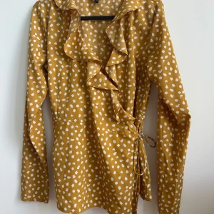 Blus - Blus med band som går att justera beroende på hur man vill att den ska sitta runt midjan