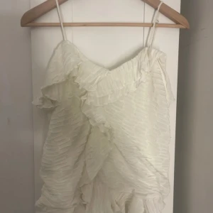 Vit volangklänning från BikBok - Supersöt vit kortklänning från BikBok med tunna axelband och volangdetaljer. Klänningen har ett plisserat tyg som ger en cool struktur och en luftig känsla. Perfekt för sommarens alla tillfällen när du vill känna dig extra fin. Helt oanvänd endast testad hann tyvärr ta bort lappen… kostar 299 ny! Priset går alltid att diskutera 💕