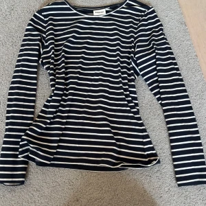 Randig långärmad tröja från Kappahl - Snygg långärmad tröja från Kappahl i marinblått och vitt med klassiskt randigt mönster. Tröjan har rund halsringning och är tillverkad i mjuk bomull, perfekt för en chill och stilren look.
