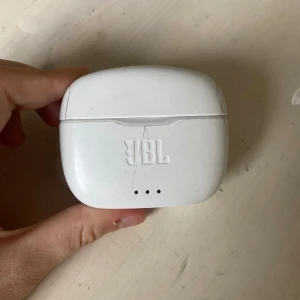 JBL Hörlurar med laddare - Säljer ett par JBL hörlurar. Perfekt för dig som vill lyssna på musik eller poddar trådlöst. Använda ett par gånger och har samt två sprickor på skalet men funkar helt utmärkt.