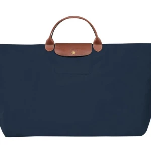Marinblå shoppingväska från Longchamp - Stilren marinblå shoppingväska från Longchamp med klassiska bruna skinnhandtag och lock. Väskan är rymlig och perfekt för dig som vill ha plats för allt. Enkel design med guldfärgad knappdetalj framtill. I storlek large och äkta!