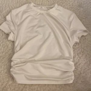 Vit basic t-shirt i bomull - Enkel och stilren vit t-shirt med rund hals och korta ärmar. Perfekt att matcha med jeans eller shorts för en clean look. Gjord i mjuk bomull som känns skön mot huden.