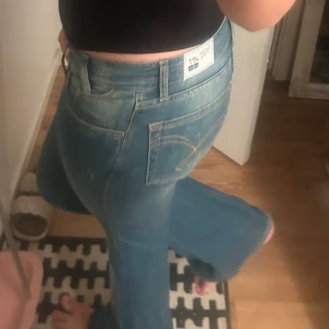 blå bootcut jeans - Säljer ett par jeans i blå low waist denim med bootcut passform. Perfekta för dig som gillar retrostil och vill ha ett par jeans med riktigt schysst passform.