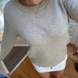 Beige stickad tröja från Vila - Beige stickad tröja från Vila med rund halsringning och ribbade muddar. Tröjan har en klassisk, enkel design och är perfekt att slänga på sig när det är lite kyligare ute. Passar dig som gillar en stilren och avslappnad look. Den sista bilden beskriver färgen på tröjan bäst!🤎