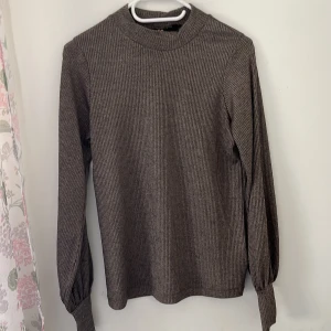 Brun ribbad långärmad tröja CC - Säljer en brun ribbad långärmad tröja från CC. Tröjan har ballongärmar med breda muddar och en rak passform. Perfekt för dig som gillar en enkel men ändå trendig look. Materialet är mjukt och stretchigt, vilket gör den superbekväm.