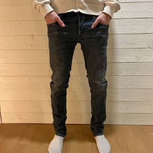 Svarta slim jeans med broderade bakfickor - Snygga jeans med diskret tvätt och broderade detaljer på bakfickorna. Modellen är slim och sitter tajt längs benen. Klassisk femficksdesign och tillverkade i stretchig denim för extra komfort.