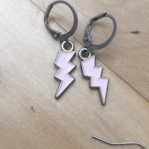 Rosa blixtörhängen i metall - Coola örhängen med blixtformade hängen i ljusrosa och silverfärgad metall. Perfekta för att ge din look en edgy touch. Säljs i par, finns både med guld och silver metallring. Unik accessoar som sticker ut! Priset gäller för ett par örhängen och det finns 16st par i lager. Man kan köpa alla 16 par för 60kr💞