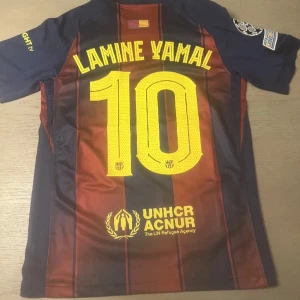  Barcelona Lamine Yamal tröja  - Säljer en FC Barcelona matchtröja med Lamine Yamal och nummer 10 på ryggen. Tröjan är kortärmad, har blå och röda ränder, gula detaljer och klubbmärke på bröstet. Materialet är lätt och andas, perfekt för fotboll eller att bära som supporter.