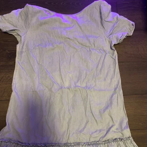 Ljusblå kort klänning med volang - Söt ljusblå kortklänning i bomull med korta ärmar och volang nertill. Enkel och avslappnad modell som passar perfekt till varmare dagar. Klänningen har en rak passform och är superenkel att styla med sneakers eller sandaler.