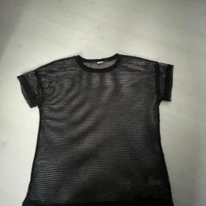 Svart meshtröja från Lindex - Cool svart meshtröja från Lindex i storlek 158/164. Tröjan är kortärmad och har ett transparent nätmönster som ger en edgy vibe. Perfekt att styla över ett linne eller crop top för en trendig look.
