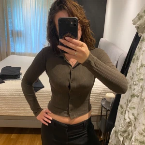 Ribbad brun kofta från Gina Tricot - Säljer en ribbad brun kofta från Gina Tricot. Modellen är figurnära med långa ärmar, knappar framtill och klassisk krage. 