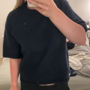 Mörkblå stickad kortärmad tröja - Säljer en mörkblå stickad tröja från Gina med korta ärmar och rund hals. Perfekt att styla med jeans eller kjol för en chill look.