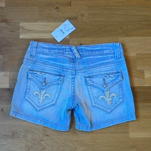 Ljusblå low rise  jeansshorts  - Superfina low waist jeansshorts med dekorativa broderade bakfickor och slitningar framtill. Köpta i Italien – unika och i väldigt fint skick! Ljus denimtvätt som passar perfekt till sommarens alla outfits 🌞  📏 Midjemått (rakt över, liggande): ca 36 cm (= ca 72 cm omkrets – motsvarar ungefär storlek S/M) 