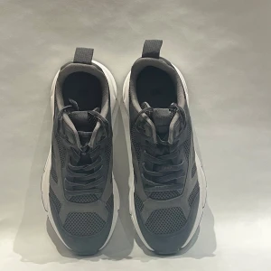 Svarta chunky sneakers från H&M - Chunky svarta sneakers från H&M i storlek 38. Ovandel i mesh och syntet med coola paneler och snörning. Vit, tjock sula ger en sportig vibe och extra komfort. Perfekta för dig som gillar streetstyle och vill ha en modern look.